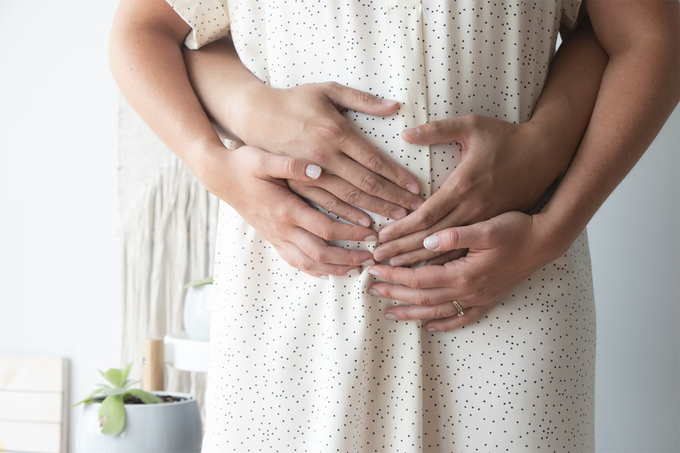 Expectant parents with their hands on the mom’s pregnant belly